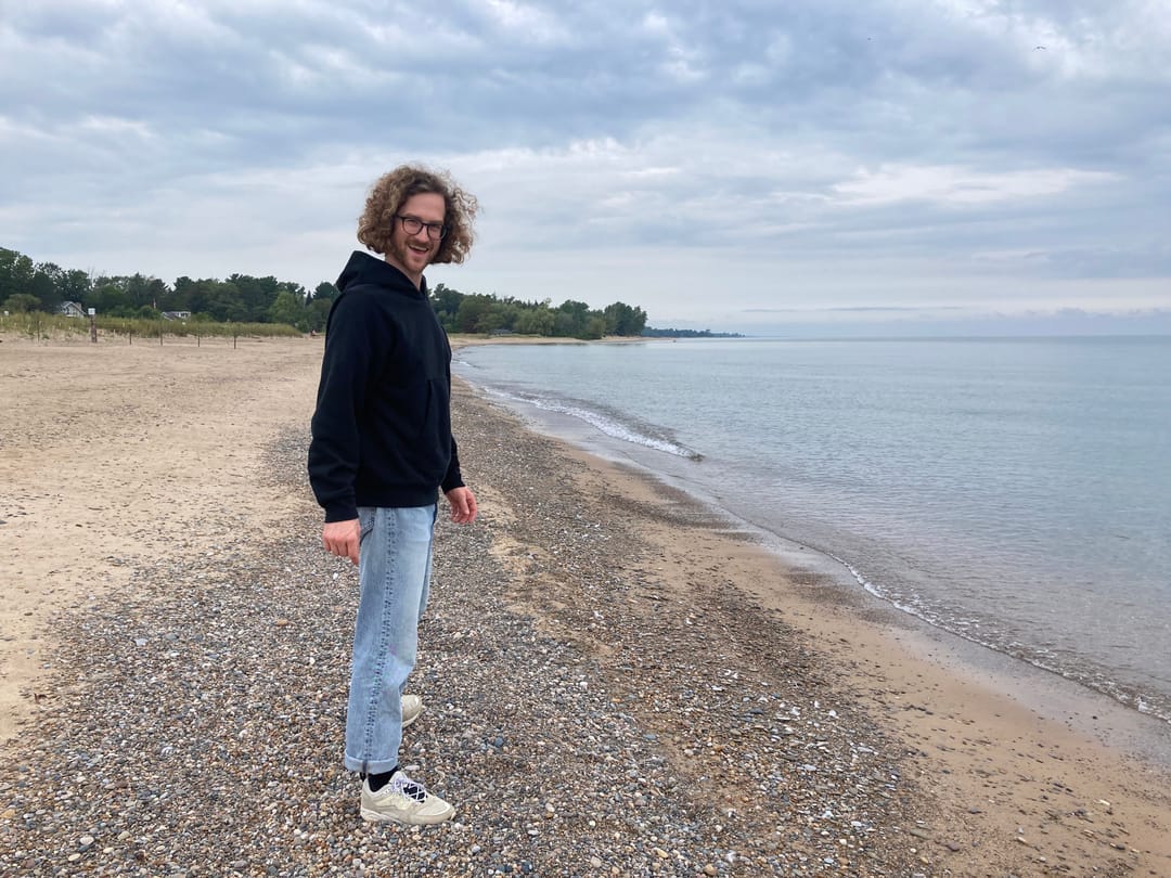 A man standing and smiling on a rocky lakeshore